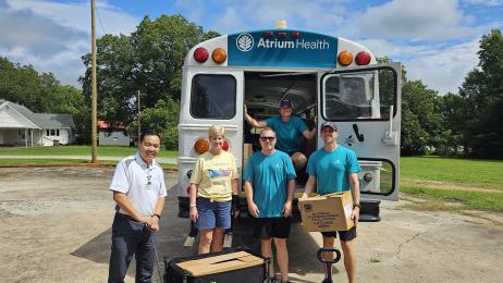 Atrium volunteers unload school supplies off the bus
