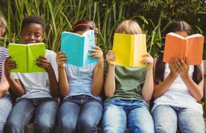 Children sitting on a wall reading books